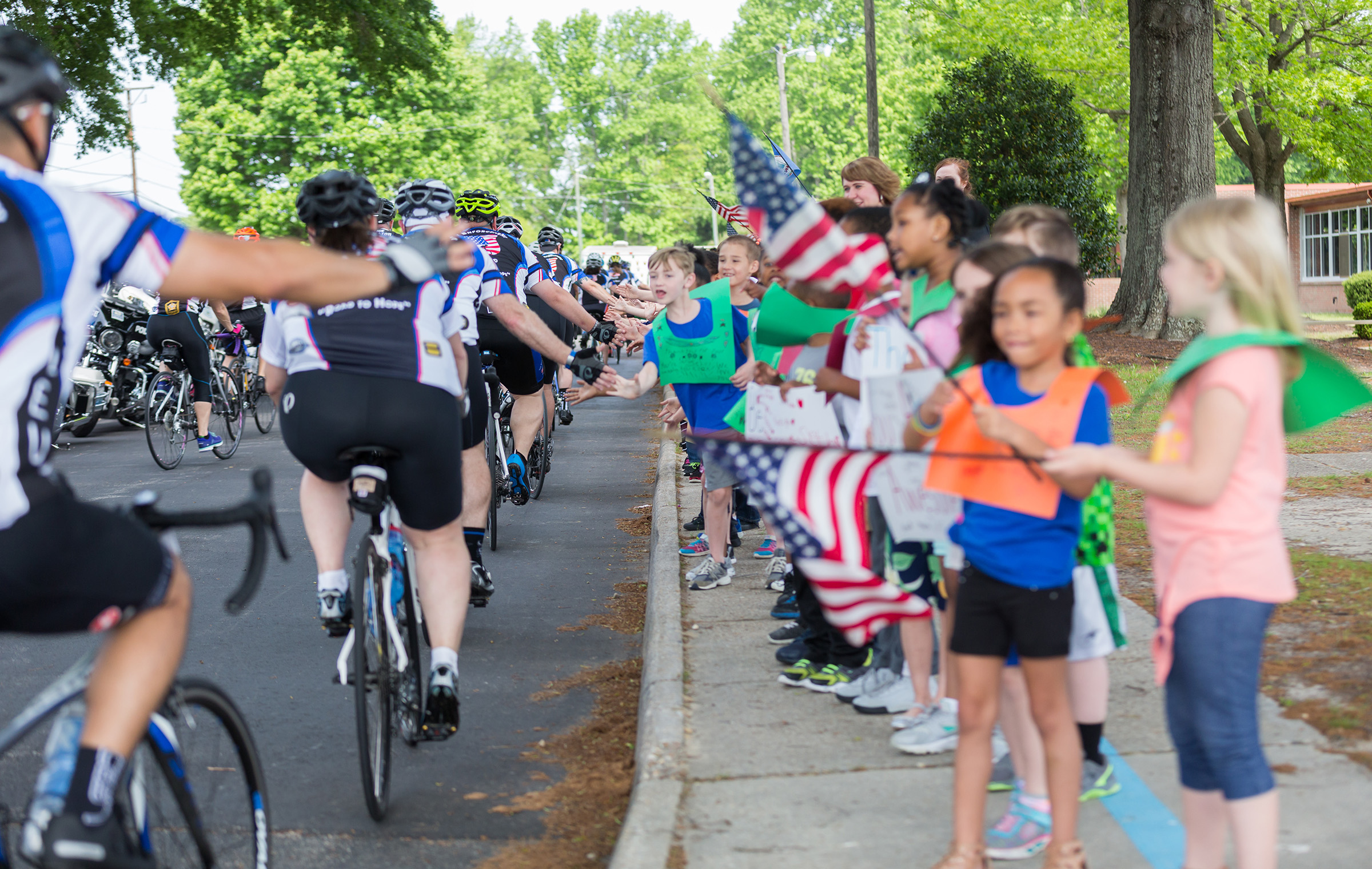 Children cheering the LEU Road to Hope cyclists on their 250-mile ride for charity.